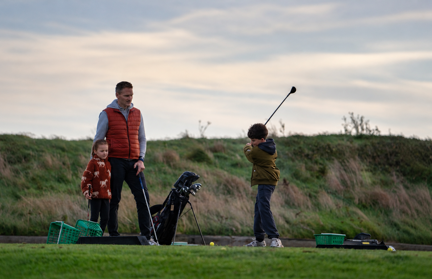 Father and two children practising golf outdoors in Irish weather